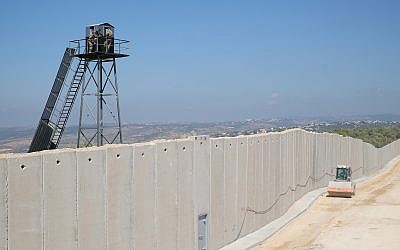 Un véhicule de construction israélien passe à côté d'un mur de béton en construction le long de la "Ligne bleue" séparant Israël et le Liban, alors que des membres des Forces armées libanaises observent depuis une tour de garde, près de la ville israélienne de Rosh Hanikra, le 5 septembre 2018. (Crédit : Judah Ari Gross/Times of Israel)