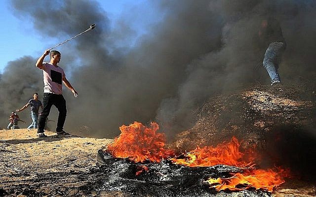 Un Palestinien avec un lance-pierres à côté de pneus brûlés lors d'affrontements à la frontière entre Israël et Gaza, à l'est de Khan Yunis, dans le sud de la bande de Gaza, le 10 août 2018. (AFP / Said Khatib) Un Palestinien avec un lance-pierres à côté de pneus brûlés lors d'affrontements à la frontière entre Israël et Gaza, à l'est de Khan Yunis, dans le sud de la bande de Gaza, le 10 août 2018. (AFP / Said Khatib)
