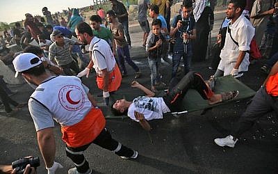 Des ambulanciers palestiniens transportent un homme blessé lors d'une manifestation au poste frontière d'Erez avec Israël, dans le nord de la bande de Gaza, le 3 octobre 2018. (AFP/Said Khatib)
