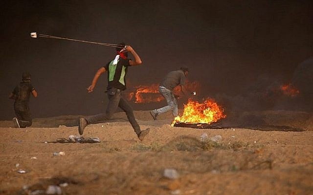 Un Palestinien jette une pierre vers les soldats israéliens durant des affrontements le long de la frontière entre la bande de Gaza et Israël à l'est de Gaza City, le 5 octobre 2018 (Crédit : AFP Photo/Said Khatib) Un Palestinien jette une pierre vers les soldats israéliens durant des affrontements le long de la frontière entre la bande de Gaza et Israël à l'est de Gaza City, le 5 octobre 2018 (Crédit : AFP Photo/Said Khatib)