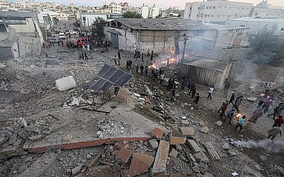 Des Palestiniens rassemblés autour des décombres d'un bâtiment de la ville de Gaza détruit par une frappe aérienne israélienne le 27 octobre 2018. (Crédit : Mahmud Hams / AFP)