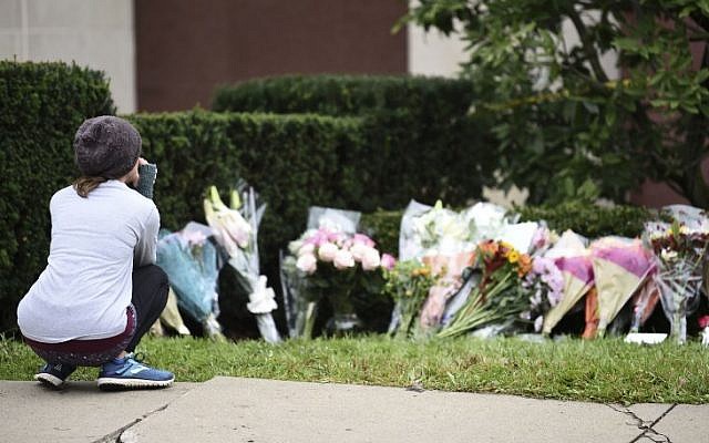 Une femme regarde les fleurs d'un mémorial aux abords de la synagogue Tree of Life de Pittsburgh, aux Etats-Unis, au lendemain d'une fusillade meurtrière, le 28 octobre 2018 (Crédit : Brendan SMIALOWSKI/AFP)