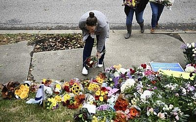 Une femme dépose des fleurs devant la synagogue Tree of life, du quartier de Squirell Hill, à Pittsburgh, après un attentat la veille dans une synagogue qui a fait 11 morts, le 28 octobre 2018. (Crédit : Brendan Smialowski / AFP) Une femme dépose des fleurs devant la synagogue Tree of life, du quartier de Squirell Hill, à Pittsburgh, après un attentat la veille dans une synagogue qui a fait 11 morts, le 28 octobre 2018. (Crédit : Brendan Smialowski / AFP)