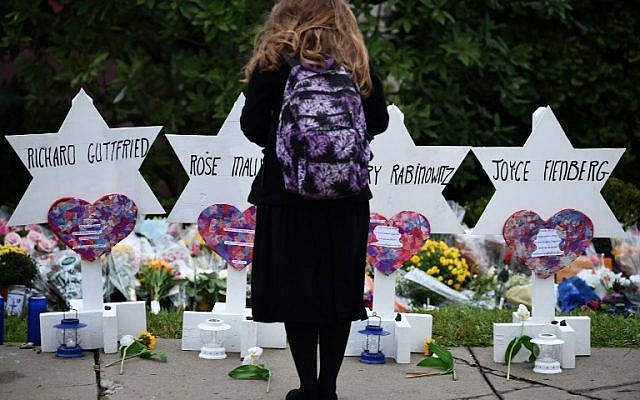 Une femme se tient devant le mémorial érigé en hommage aux victimes de la fusillade de la synagogue Tree of life, à Pittsburgh, (Crédit : Brendan SMIALOWSKI / AFP) Une femme se tient devant le mémorial érigé en hommage aux victimes de la fusillade de la synagogue Tree of life, à Pittsburgh, (Crédit : Brendan SMIALOWSKI / AFP)