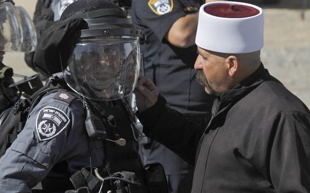 Un homme druze s'entretient avec un policier lors d'une manifestation contre les élections municipales devant un bureau de vote du village de Majdal Shams le 30 octobre 2018. (Crédit : JALAA MAREY / AFP) Un homme druze s'entretient avec un policier lors d'une manifestation contre les élections municipales devant un bureau de vote du village de Majdal Shams le 30 octobre 2018. (Crédit : JALAA MAREY / AFP)