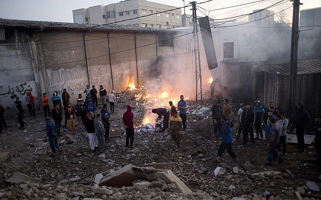 Les Palestiniens vérifient les dégâts causés aux bâtiments détruits par les frappes aériennes israéliennes à Gaza le 27 octobre 2018 après des tirs de roquettes depuis Gaza. (Crédit : AP / Khalil Hamra)