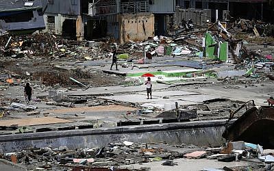 Un homme sous un parapluie dans un quartier du village de Wani, dans la banlieue de Palu, dans le centre de Sulawesi, en Indonésie, le 4 octobre 2018 (Crédit : Dita Alangkara/AP)