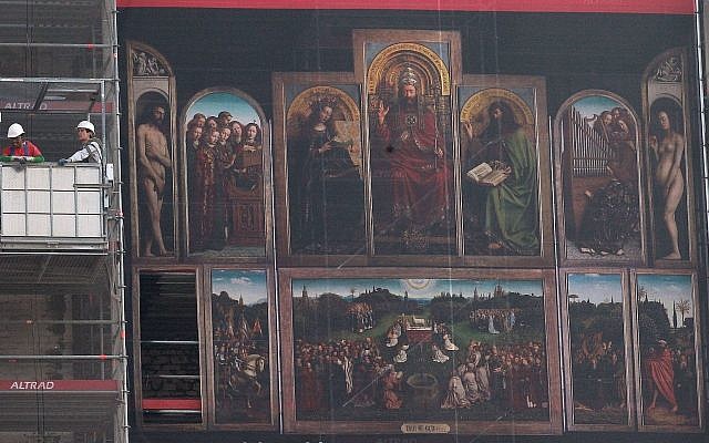 Des ouvriers dans une nacelle à côté de la reproduction géante de l'oeuvre de 'l'Adoration de l'Agneau mystique' du peintre flamand Jan van Eyck pendant la rénovation de la cathédrale Saint-Bavo de Gand, en Belgique, le 13 mars 2014 (Crédit : AP Photo/Yves Logghe)