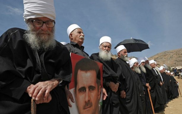 Des membres de la communauté druze tenant le portrait du président syrien Bashar el-Assad lors d'un rassemblement dans le village druze de Majdal Shams dans les hauteurs du Golan israélien, le 6 octobre 2018, commémorant le 45e anniversaire de la guerre israélo-arabe de 1973. (AFP PHOTO / JALAA MAREY)