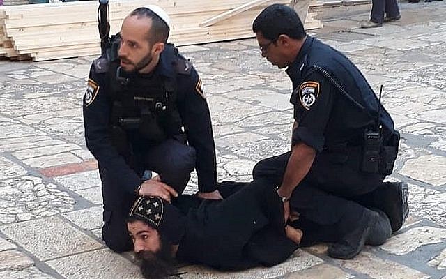 Des officiers de police israéliens retiennent un clerc copte lors d'une manifestation contre des travaux dans l'église du Saint-Sépulcre dans la Vieille Ville de Jérusalem, le 24 octobre 2018. (Crédit : patriarcat des Coptes orthodoxes à Jérusalem / Facebook) Des officiers de police israéliens retiennent un clerc copte lors d'une manifestation contre des travaux dans l'église du Saint-Sépulcre dans la Vieille Ville de Jérusalem, le 24 octobre 2018. (Crédit : patriarcat des Coptes orthodoxes à Jérusalem / Facebook)