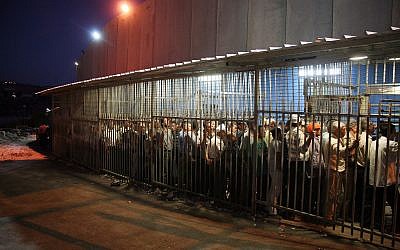 Des travailleurs palestiniens attendent à un check point à la barrière de sécurité, dans la ville de Bethléem, en Cisjordanie, le 23 août 2010 (Crédit : Najeh Hashlamoun/Flash 90)