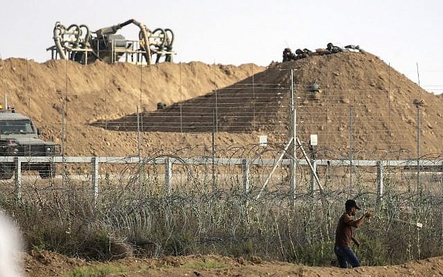 Un Palestinien utilise une fronde pour jeter une pierre aux soldats israéliens de l'autre côté de la frontière lors d'affrontements à l'est de Gaza City, le 13 juillet 2018 (Crédit : AFP PHOTO / MAHMUD HAMS) Un Palestinien utilise une fronde pour jeter une pierre aux soldats israéliens de l'autre côté de la frontière lors d'affrontements à l'est de Gaza City, le 13 juillet 2018 (Crédit : AFP PHOTO / MAHMUD HAMS)