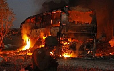 Les forces de sécurité et les pompiers israéliens convergent vers un bus incendié après avoir été touché par une roquette tirée depuis l'enclave palestinienne, à la frontière entre Israël et Gaza, près du kibboutz de Kfar Aza, le 12 novembre 2018. (Crédit : Menahem KAHANA / AFP)