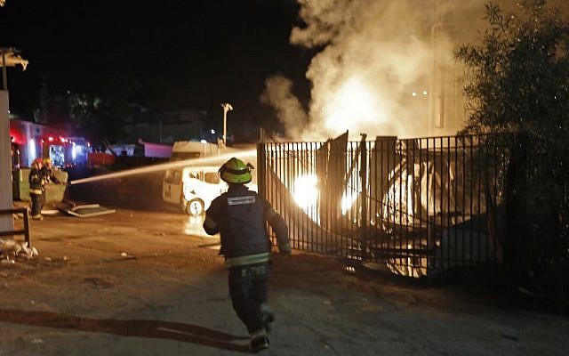 Les forces de sécurité et les pompiers israéliens se rassemblent près d'un bâtiment incendié après avoir été touché par une roquette tirée depuis la bande de Gaza, dans la ville de Sderot, dans le sud du pays, le 12 novembre 2018. (Crédit : Menahem KAHANA / AFP)