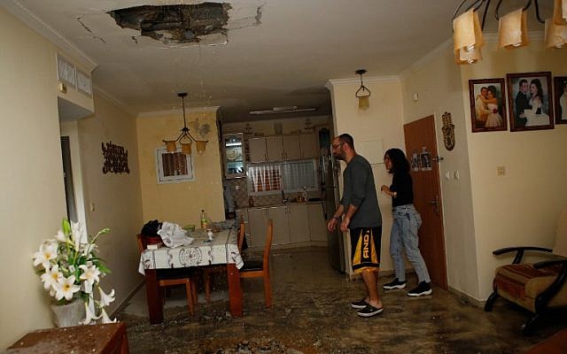 Des Israéliens inspectent les dégâts dans un appartement touché par une roquette lancée depuis la bande de Gaza, dans la ville d'Ashkelon, dans le sud d'Israël, le 12 novembre 2018. (Crédit : GIL COHEN-MAGEN / AFP)