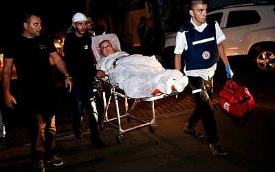 Une femme israélienne blessée, évacuée de son appartement incendié après avoir été touché par une roquette tirée depuis la bande de Gaza, est escortée à l'hôpital sur une civière dans la ville d'Ashkelon, dans le sud d'Israël, le 12 novembre 2018. (Crédit : GIL COHEN-MAGEN / AFP)