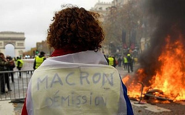 Une femme avec un "Gilet jaune" manifeste contre les hausses du prix des carburants et du coût de la vie près de l'Arc de Triomphe, aux Champs Elysées, le 24 novembre 2018 (Crédit : y Bertrand GUAY / AFP) Une femme avec un "Gilet jaune" manifeste contre les hausses du prix des carburants et du coût de la vie près de l'Arc de Triomphe, aux Champs Elysées, le 24 novembre 2018 (Crédit : y Bertrand GUAY / AFP)