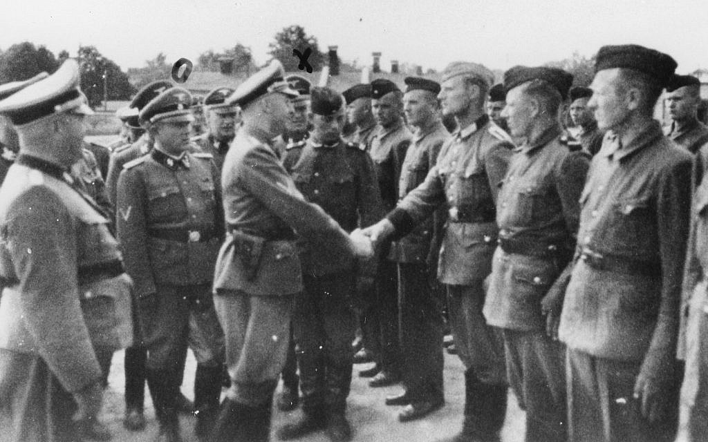 Sur cette photo de 1942 fournie par le bureau du procureur de Hambourg, Heinrich Himmler, au centre gauche, serre la main aux nouvelles recrues du camp de concentration de Trawniki dans la Pologne occupée par les nazis (Crédit :  bureau du procureur de Habourg via le musée du mémorial de la Shoah des Etats-Unis via l'AP)