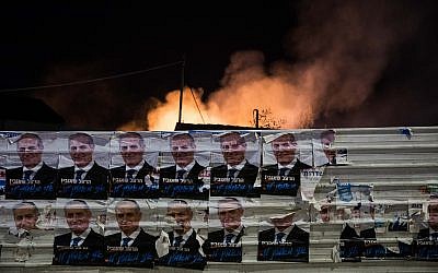 Des affiches de campagne électorale devant la fumée émanant d'un bâtiment incendié par une roquette de la bande de Gaza dans le sud d'Israël, à Sdérot, le 12 novembre 2018 (Crédit : Hadas Parush/Flash90) Des affiches de campagne électorale devant la fumée émanant d'un bâtiment incendié par une roquette de la bande de Gaza dans le sud d'Israël, à Sdérot, le 12 novembre 2018 (Crédit : Hadas Parush/Flash90)