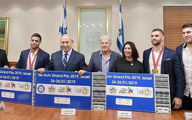 Le Premier ministre Benjamen Netanyahu et la ministre de la Culture et des Sports Miri Regev, entourés par l'équipe de judo israélienne présentent les futurs tickets pour le Grand Prix 2019 de Tel Aviv. (Crédit photo : GPO)