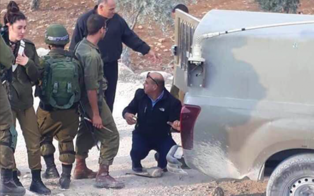 Le 11 novembre 2018, le colonel Ahmed Abu al-Rub, chef de la police de l'Autorité palestinienne à Hébron, aide les soldats israéliens à remplacer un pneu d'un véhicule militaire. (Crédit : capture d'écran Twitter)