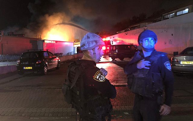 Des policiers se tiennent près d'un incendie d'un immeuble à Sdérot le 12 novembre 2018. (Crédit : Police israélienne)