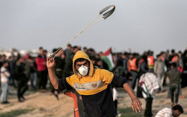 Un Palestinien lance une pierre vers les forces israéliennes pendant des affrontements sur la frontière avec la bande de Gaza, le 30 novembre 2018 (Crédit :  MAHMUD HAMS / AFP)
