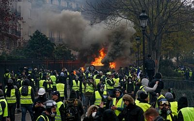 Des manifestants se rassemblent autour d'une voiture en feu lors d'une manifestation des Gilets jaunes contre la hausse du prix du pétrole et du coût de la vie, le 1er décembre 2018 à Paris. (Geoffroy VAN DER HASSELT / AFP)