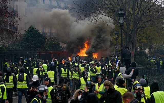 Des manifestants se rassemblent autour d'une voiture en feu lors d'une manifestation des Gilets jaunes contre la hausse du prix du pétrole et du coût de la vie, le 1er décembre 2018 à Paris. (Geoffroy VAN DER HASSELT / AFP)