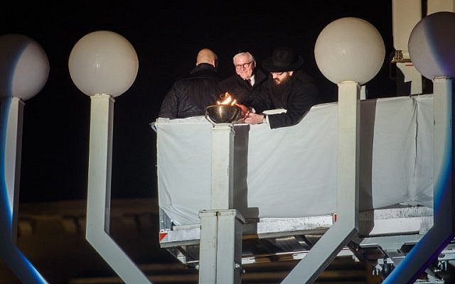 Le président allemand Frank-Walter Steinmeier, au centre, et le rabbin  Yehuda Teichtal, à droite, allument un candélabre devant la porte de Brandenburg à Berlin, le 2 décembre 2018 (Crédit :  Gregor Fischer / dpa / AFP)