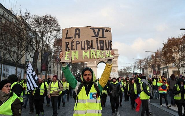 Un manifestant portant un "gilet jaune" réclame l'instauration d'une VIe République, à Paris le 8 décembre 2018, lors d'une manifestation contre la hausse du coût de la vie que les gilets jaunes imputent aux impôts élevés. (Crédit : Zakaria ABDELKAFI / AFP) Un manifestant portant un "gilet jaune" réclame l'instauration d'une VIe République, à Paris le 8 décembre 2018, lors d'une manifestation contre la hausse du coût de la vie que les gilets jaunes imputent aux impôts élevés. (Crédit : Zakaria ABDELKAFI / AFP)