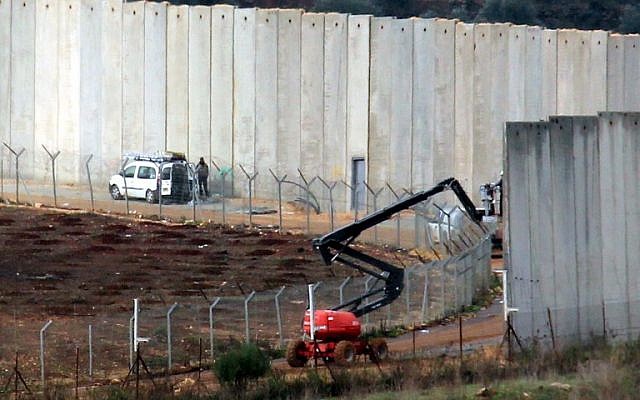 Des Israéliens travaillent près du mur frontalier en béton séparant les deux pays, une photo prise au sud du village libanais de Kfar Kila, à la frontière avec Israël, le 9 décembre 2018 (Crédit : Ali DIA / AFP) Des Israéliens travaillent près du mur frontalier en béton séparant les deux pays, une photo prise au sud du village libanais de Kfar Kila, à la frontière avec Israël, le 9 décembre 2018 (Crédit : Ali DIA / AFP)