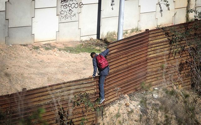 TIJUANA, MEXIQUE: Un migrant traverse la frontière entre les Etats Unis et le Mexique avant de se rendre à la police des frontières américaine, le 16 décembre 2018. (Crédit : Mario Tama/Getty Images/AFP)