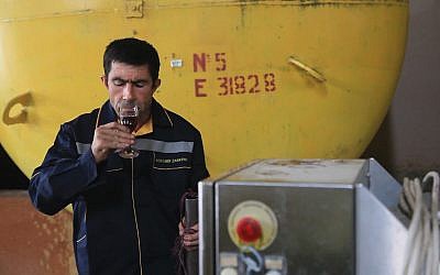 Un Ouzbèque goûte le vin dans une entreprise vinicole. (Crédit : Stanislav KHODJAEV / AFP)