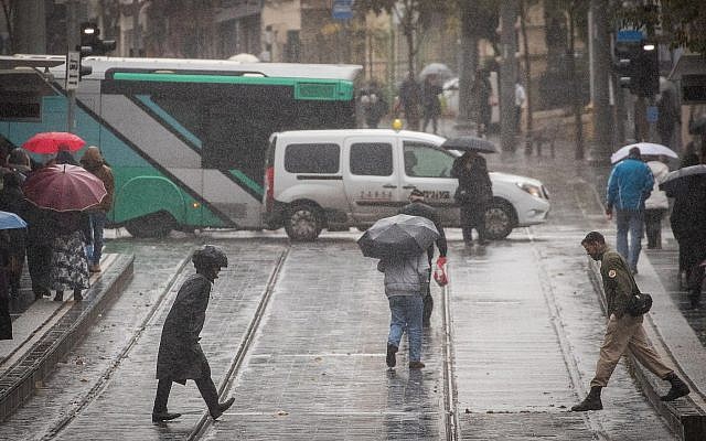 Des gens marchent Route de Jaffa, à Jérusalem, sous la pluie, le 6 décembre 2018 (Crédit : Yonatan Sindel/Flash90)