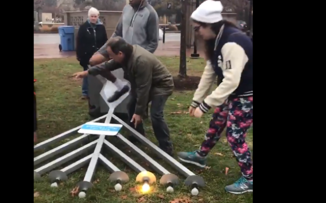 Des personnes aident à remettre sur pied une hannoukiah qu a été renversée à Cambrigde, dans le Massachusetts, le 3 décembre, 2018 (Crédit : capture d'écran/Twitter) Des personnes aident à remettre sur pied une hannoukiah qu a été renversée à Cambrigde, dans le Massachusetts, le 3 décembre, 2018 (Crédit : capture d'écran/Twitter)