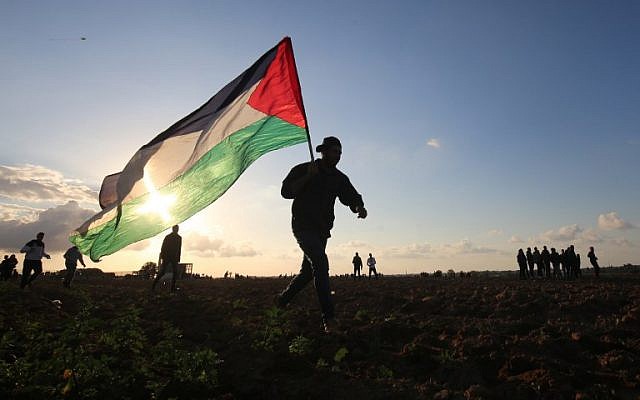 Un manifestant palestinien porte un drapeau national lors d'une manifestation près de la frontière entre Israël et Khan Younès dans le sud de la bande de Gaza, le 21 décembre 2018. (Photo par SAID KHATIB / AFP) Un manifestant palestinien porte un drapeau national lors d'une manifestation près de la frontière entre Israël et Khan Younès dans le sud de la bande de Gaza, le 21 décembre 2018. (Photo par SAID KHATIB / AFP)