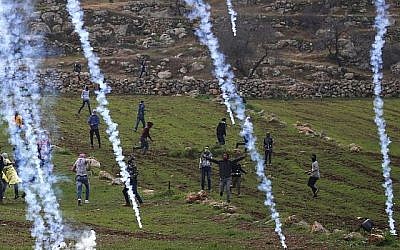 Des gaz lacrymogènes lancés sur des émeutiers palestiniens durant un affrontement dans le village de Mughayir,en Cisjordanie, le 27 janvier 2019. (Crédit : ABBAS MOMANI / AFP) Des gaz lacrymogènes lancés sur des émeutiers palestiniens durant un affrontement dans le village de Mughayir,en Cisjordanie, le 27 janvier 2019. (Crédit : ABBAS MOMANI / AFP)