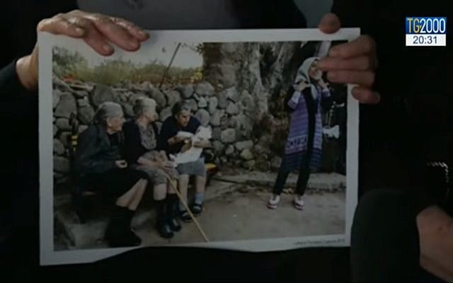 Maritsa Mavrapidou et deux autres femmes âgées de Lesbos sont devenues célèbres en 2015 lorsqu'elles ont été photographiées en train de donner le biberon à un bébé dont les parents venaient de débarquer sur l'île après une périlleuse traversée de la Mer Egée. (Crédit : capture d'écran YouTube) Maritsa Mavrapidou et deux autres femmes âgées de Lesbos sont devenues célèbres en 2015 lorsqu'elles ont été photographiées en train de donner le biberon à un bébé dont les parents venaient de débarquer sur l'île après une périlleuse traversée de la Mer Egée. (Crédit : capture d'écran YouTube)