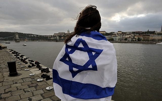 Une jeune fille juive hongroise, couverte d'un drapeau israélien, devant le mémorial de chaussures commémorant les victimes de la Shoah sur la rive du Danube lors de la commémoration de la Journée de la Shoah en Hongrie, mercredi 16 avril 2008 à Budapest (Crédit : AP/Bela Szandelszky) Une jeune fille juive hongroise, couverte d'un drapeau israélien, devant le mémorial de chaussures commémorant les victimes de la Shoah sur la rive du Danube lors de la commémoration de la Journée de la Shoah en Hongrie, mercredi 16 avril 2008 à Budapest (Crédit : AP/Bela Szandelszky)