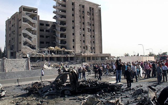 Illustration : des Syriens rassemblés devant une immeuble du renseignement militaire où deux bombes ont explosé, à Damas, le 10 mai 2012. (Crédit : Bassem Tellawi/AP)