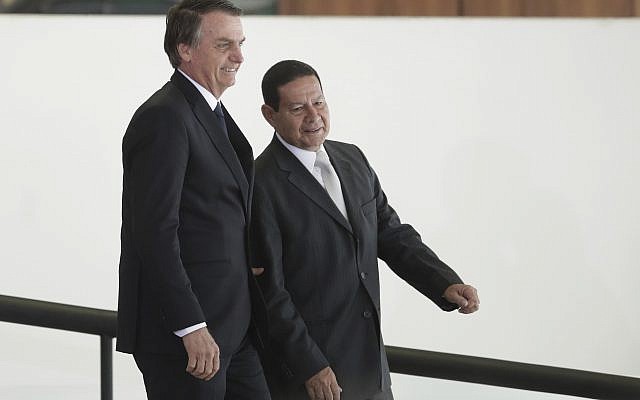 Le président brésilien Jair Bolsonaro, à gauche, se rend avec son vice-président Hamilton Mourao à une cérémonie au cours de laquelle les présidents des banques d'État du pays seront présentés au palais présidentiel Planalto de Brasilia, au Brésil, le lundi 7 janvier 2019. (Crédit :  AP / Eraldo Peres)
