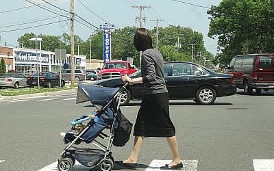 Une femme orthodoxe pousse une poussette à Lakewood (New Jersey) en 2013. La population de la ville orthodoxe en grande partie haredi a explosé au cours des deux dernières décennies, et les familles haredi cherchent à s'installer dans les villes voisines. (Dennis Fraevich/Flickr via JTA)
