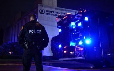 Un agent de police sous la pluie aux abords de la synagogue Tree of Life après une fusillade qui a fait onze morts dans le quartier de Squirrel Hill à  Pittsburgh le 27 octobre 2018 (Crédit : Brendan Smialowski / AFP)