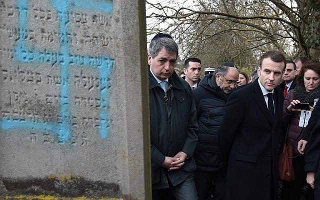 Le président français Emmanuel Macron observe une tombe vandalisée d'une croix gammée lors d'une visite au cimetière juif de Quatzenheim, le 19 février 2019, le jour des marches nationales contre la montée des attaques antisémites. (Photo par Frederick FLORIN / POOL / AFP) Le président français Emmanuel Macron observe une tombe vandalisée d'une croix gammée lors d'une visite au cimetière juif de Quatzenheim, le 19 février 2019, le jour des marches nationales contre la montée des attaques antisémites. (Photo par Frederick FLORIN / POOL / AFP)