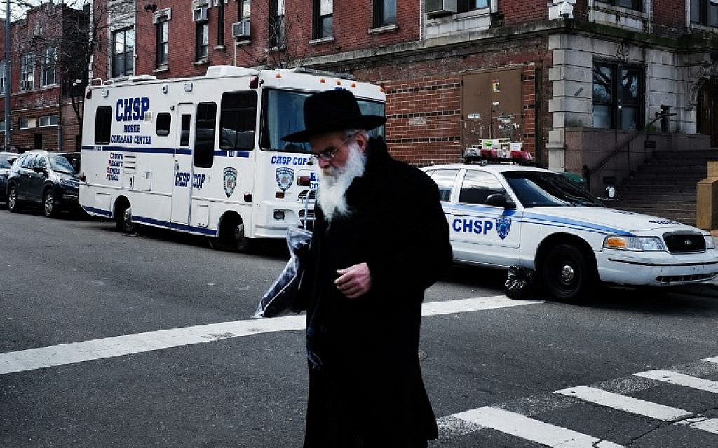 Des juifs orthodoxes dans le quartier de Crown Heights, à Brooklyn, le 27 février 2019. En arrière plan, un véhicule de la Crown Heights Shmira Patrol, une patroulle de sécurité mise en place par la communauté juive, dans un contexte d'antisémitisme ambiant. (Crédit : Angela Weiss / AFP)