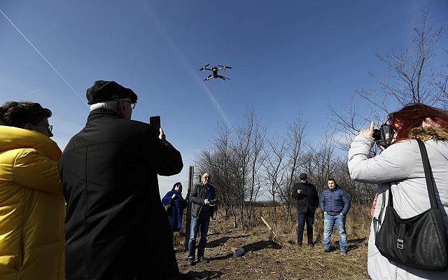 Des participants à une conférence organisée par la Fondation de l'Initiative des cimetières juifs européens (EJCI), basée en Allemagne, observent un drone décoller au-dessus d'un cimetière juif à proximité du village de Reca, en Slovaquie, le mardi 26 février 2019. (AP Photo/Petr David Josek) Des participants à une conférence organisée par la Fondation de l'Initiative des cimetières juifs européens (EJCI), basée en Allemagne, observent un drone décoller au-dessus d'un cimetière juif à proximité du village de Reca, en Slovaquie, le mardi 26 février 2019. (AP Photo/Petr David Josek)