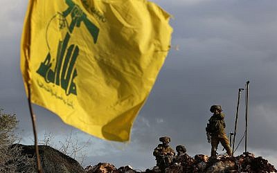 Dans cette photo du 13 décembre 2018, des soldats israéliens montent la garde à côté de caméras dans leur nouvelle position en face d'un drapeau du Hezbollah, à proximité du village frontalier Mays al-Jabal du sud du Liban. (AP Photo/Hussein Malla)