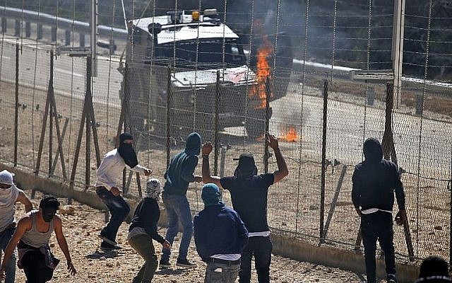 Un véhicule de l'armée israélienne en flammes durant des heurts avec des Palestiniens dans le village palestinien de Beit Sira, en Cisjordanie, le 8 mars 2019. (Crédit : Abbas Momani/AFP)