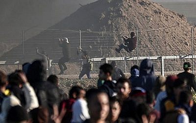 Des Palestiniens escaladent la clôture de sécurité à la frontière avec Israël lors d'affrontements dans l'est de la bande de Gaza, le 8 mars 2019 (Crédit : MAHMUD HAMS / AFP)
